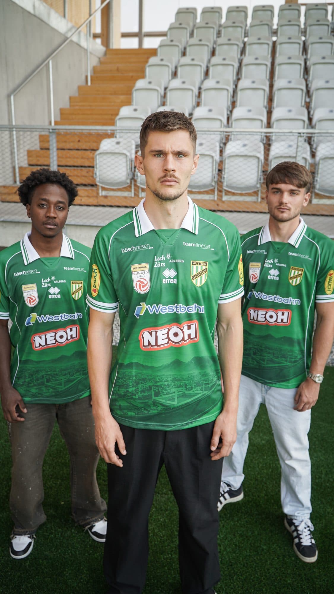 Drei Spieler von Austria Lustenau im Heimtrikot 26/27 auf der Tribüne